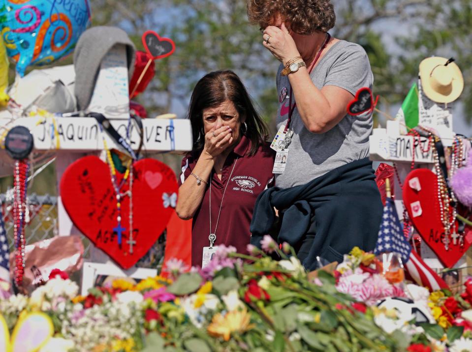  Marjory Stoneman Douglas High School administrative employees Margarita LaSalle, left, and JoEllen Berman, walk along the hill near the school lined with 17 crosses to honor the students and teachers killed on Valentine's Day