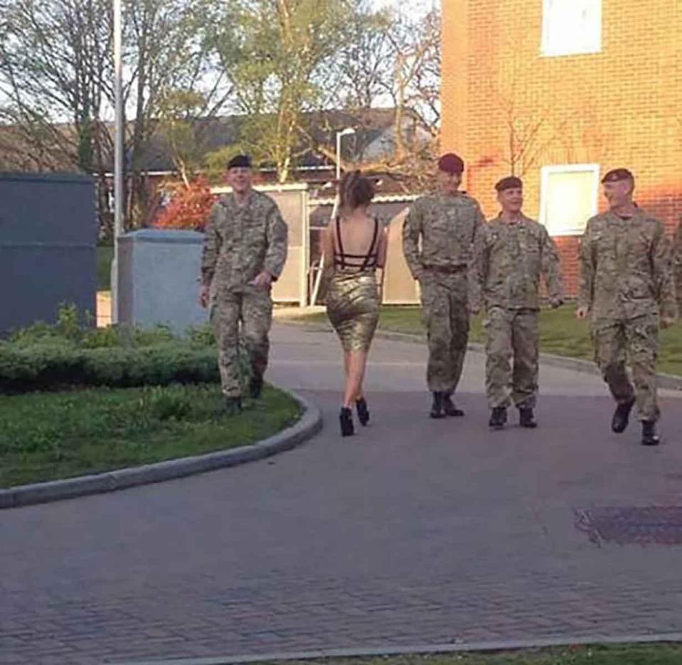  This young woman almost blends in as she passes soldiers on her way home