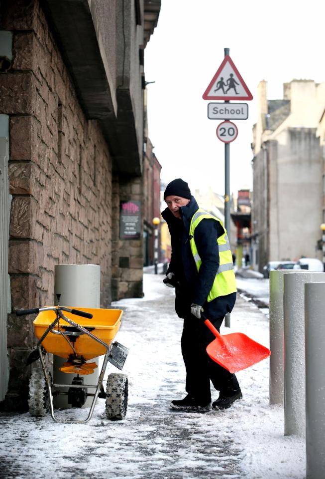  A man clears snow from pavements along Edinburgh's Royal Mile