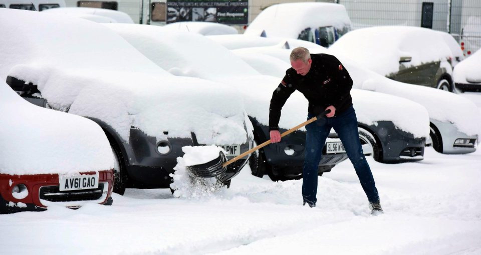  Staff clear snow from cars at Swale Auto Sales in Catterick, North Yorkshire