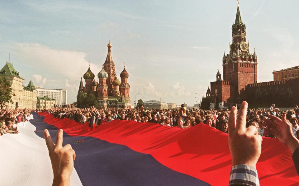  People holding a huge Russian flag flash victory signs on August 22, 1991 at Red Square, Moscow