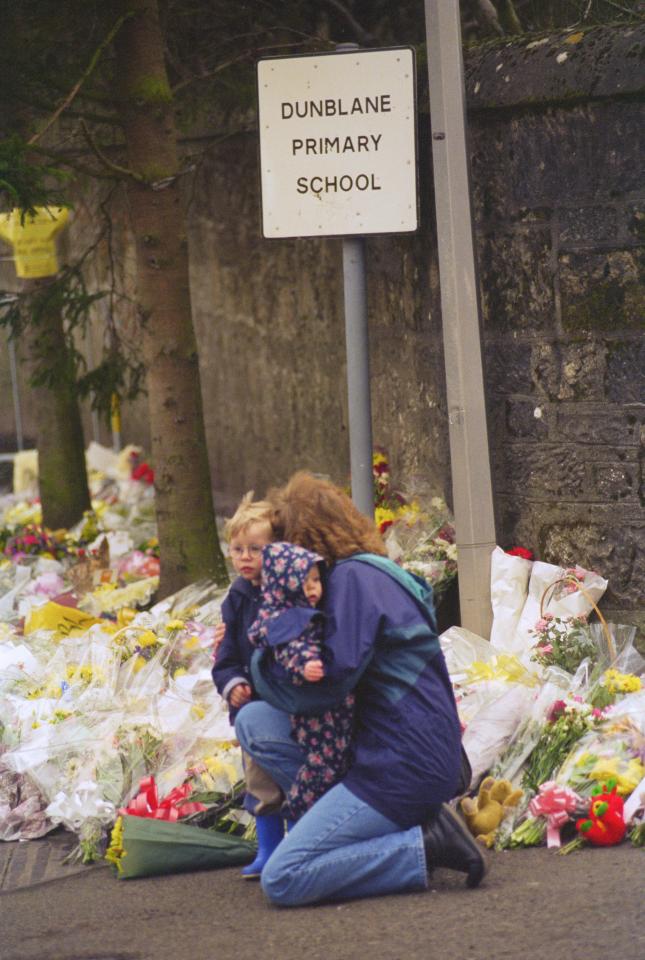  A woman laying a bouquet alongside countless others at the Dunblane Primary School in Scotland, the site of a gun massacre in 1996