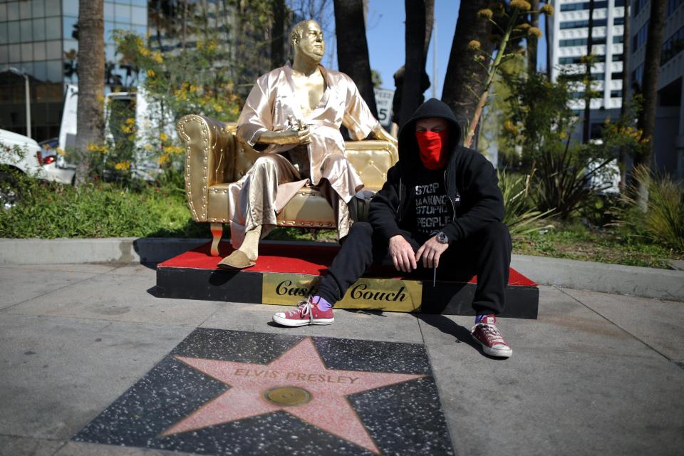  Street artist Plastic Jesus next to the 'Casting Couch' statue on Hollywood Boulevard