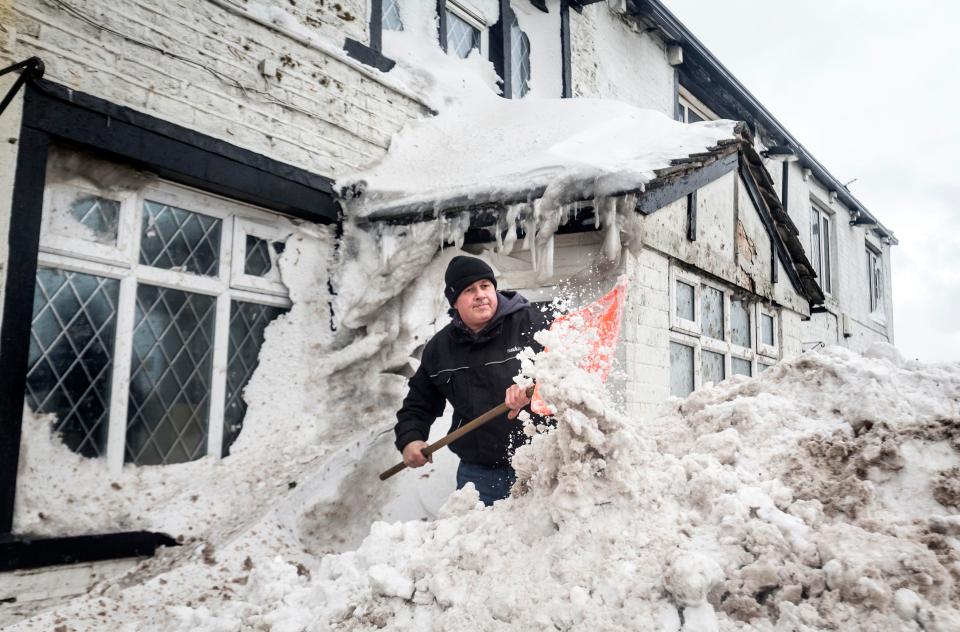  Landlord Angus Wharton clears snow outside the Ye Olde Black Ladd pub in Shaw, Greater Manchester