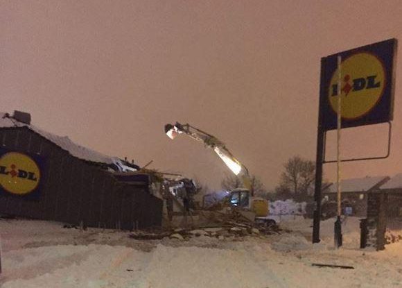  A digger was filmed ripping the roof off the supermarket as crowds watched on