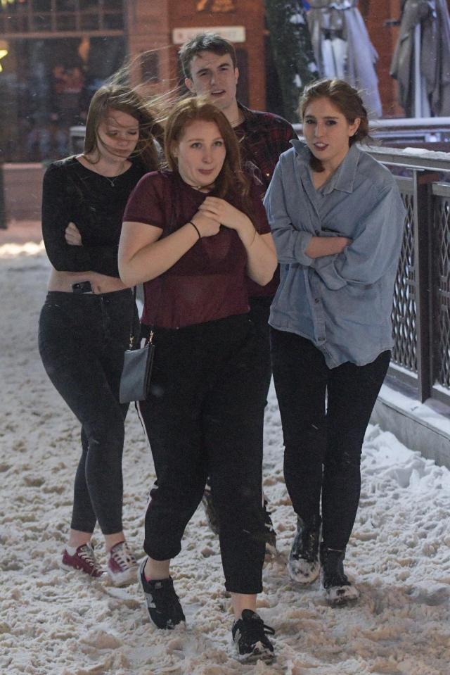 A group shiver in the freezing temperatures as they wear thin tops and go on a night out on a snow covered Broad Street in Birmingham 