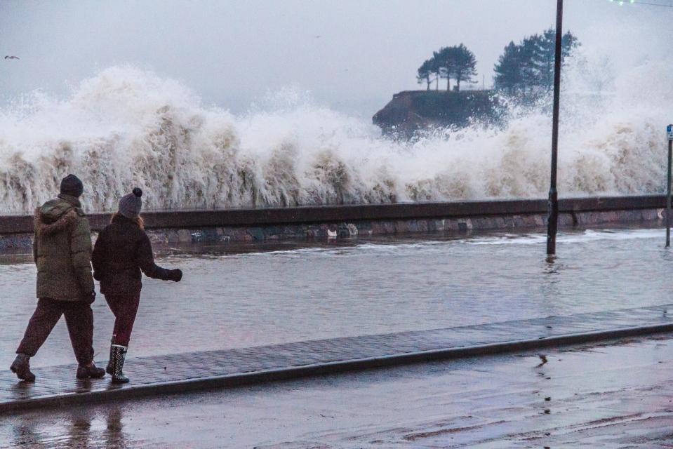 The big thaw is set to cause major flooding. Two locals in Devon watch on yesterday morning as waves crash against a barrier