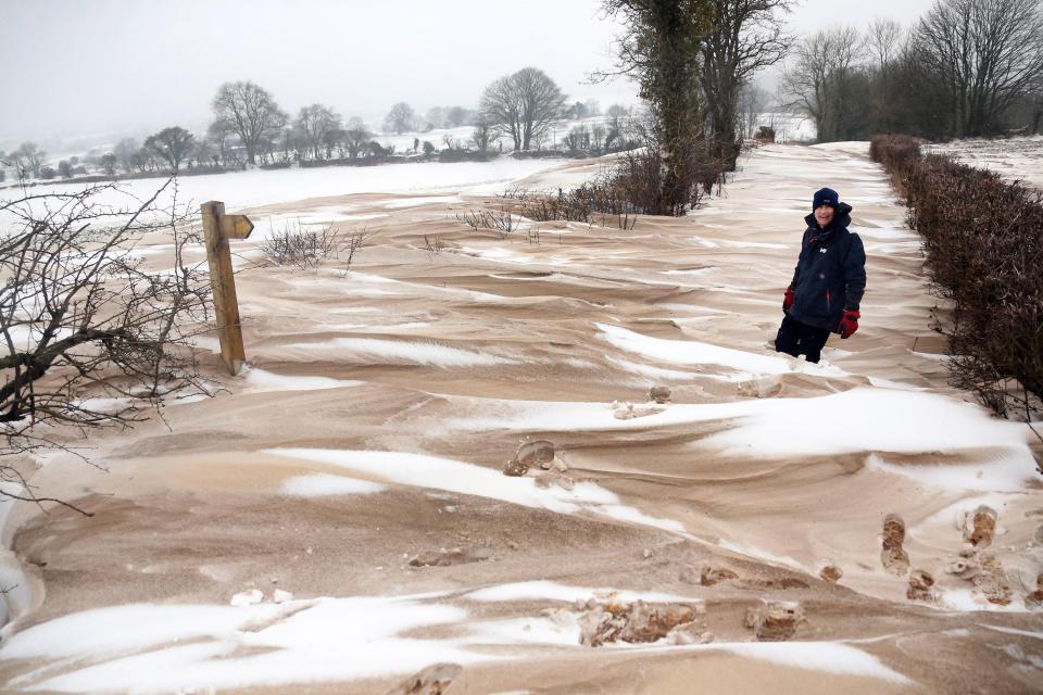  A local man walks over a snow drift blocked road at Bodden near Shepton Mallet, Somerset