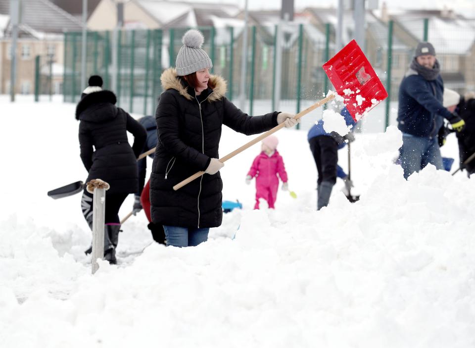 A woman begins clearing the grounds of Kinnaird Primary School, in Larbert, Scotland, as the cold weather continues around the country