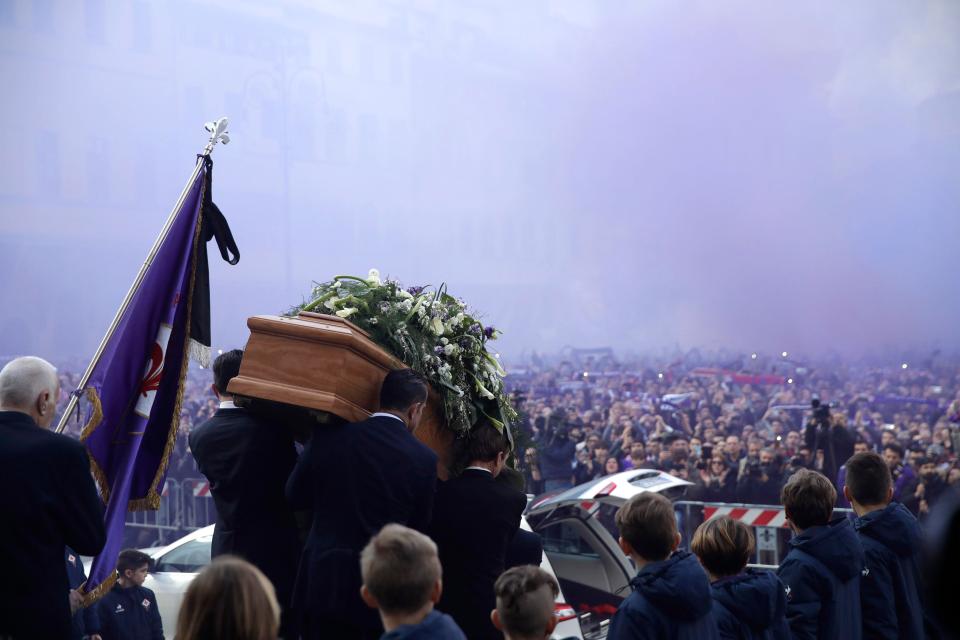 Astori's coffin is taken towards the hearse after the funeral service as purple smoke fills the Piazza from fans' flares