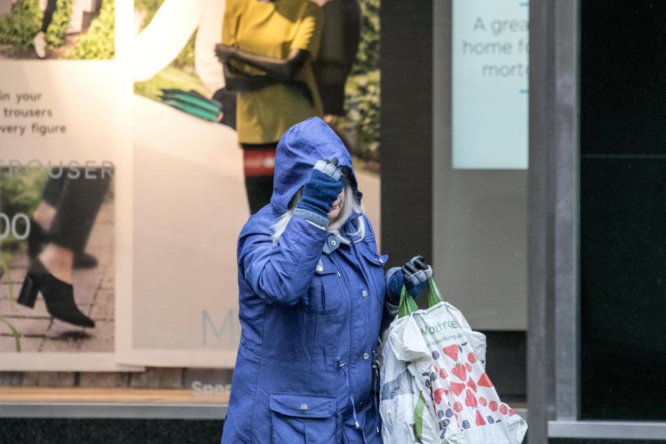  A woman takes cover under her hood as the heavens open in Merseyside