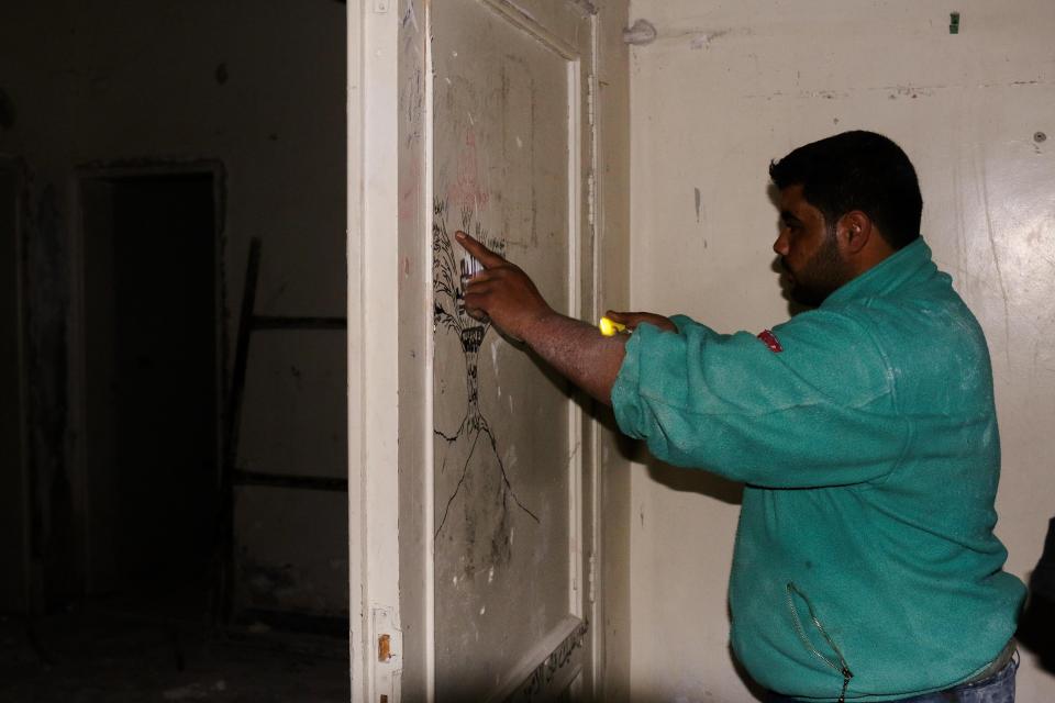  Rambo points to an ISIS oath tree painted on the prison wall