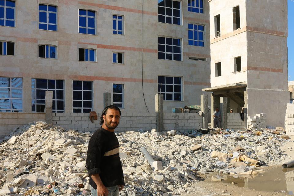  Abdullah stands next to hotel entrance