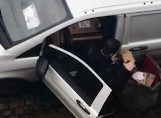  A delivery driver is pictured rifling through Amazon parcels during rounds in East London