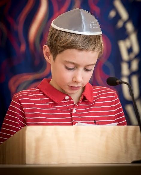 Stacey’s son Zachary wears a kippah and reads a passage at his Uncle Josh’s Bar Mitzvah