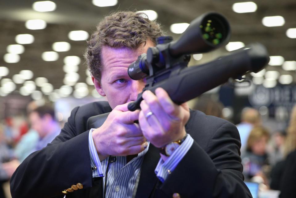  An attendee at the NRA's 2018 convention looks down the sight of a rifle