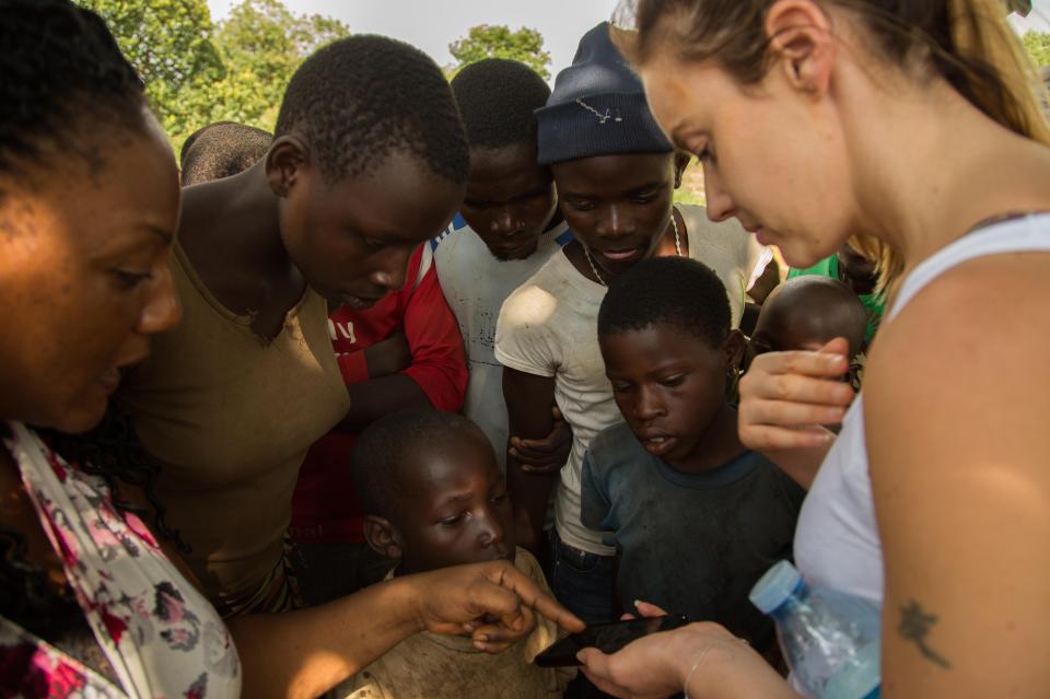  Curious locals inspect Charlie's phone during her visit