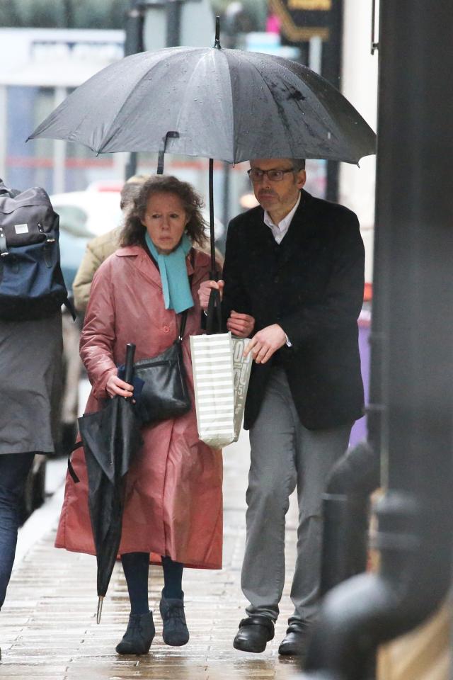  Sonia held onto Michael as he held an umbrella over both of them