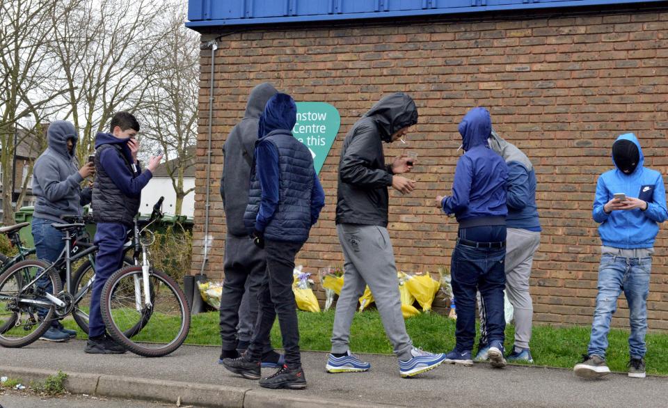  A number of young men covered their faces as they left flowers at the scene