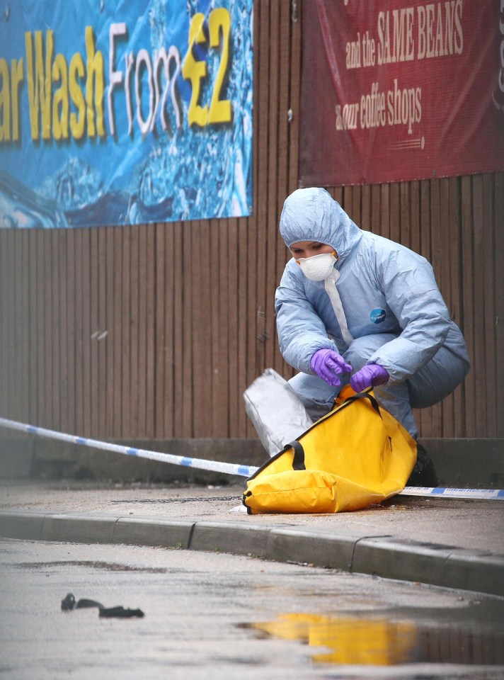 A forensic officer combs the Esso garage forecourt for clues