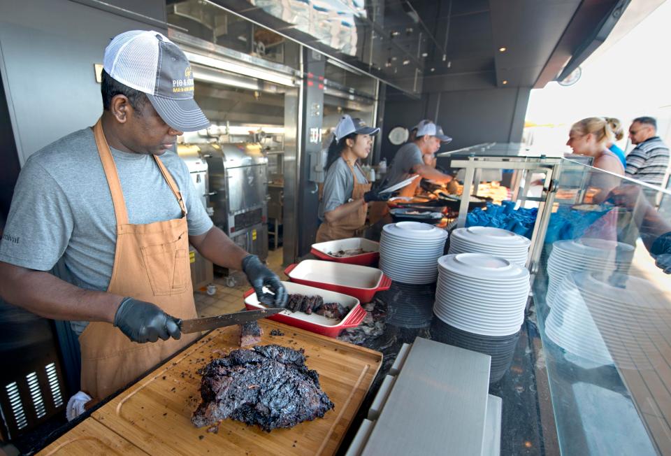  A Carnival Horizon staff member carves up smoked meat at Guy's Pig & Anchor Smokehouse|