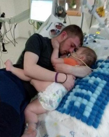  Tom holds his son close in his hospital bed in a touching image before the youngster died