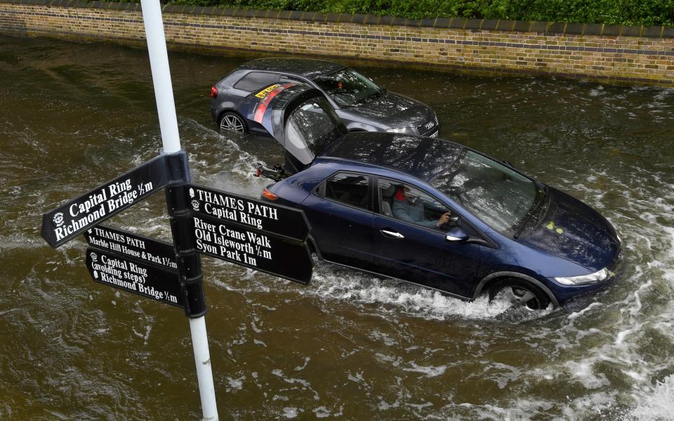  Cars drive along a flooded street in London after the Thames burst its banks