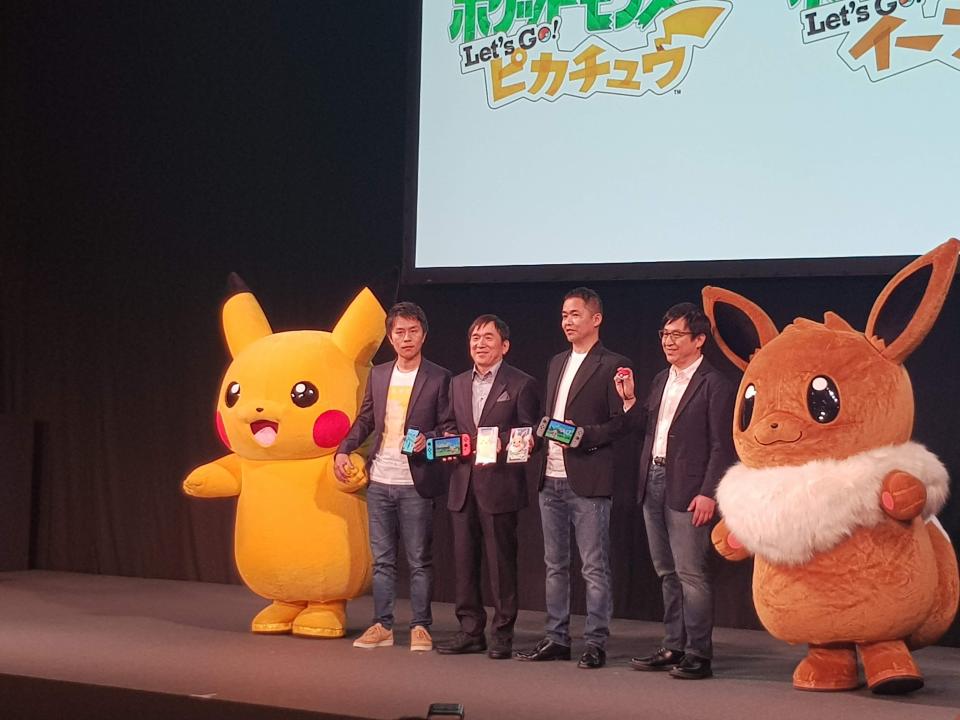  Pokemon and GameFreak executives pose with Pikachu, Eevee, the new games and the Pokeball Plus controller