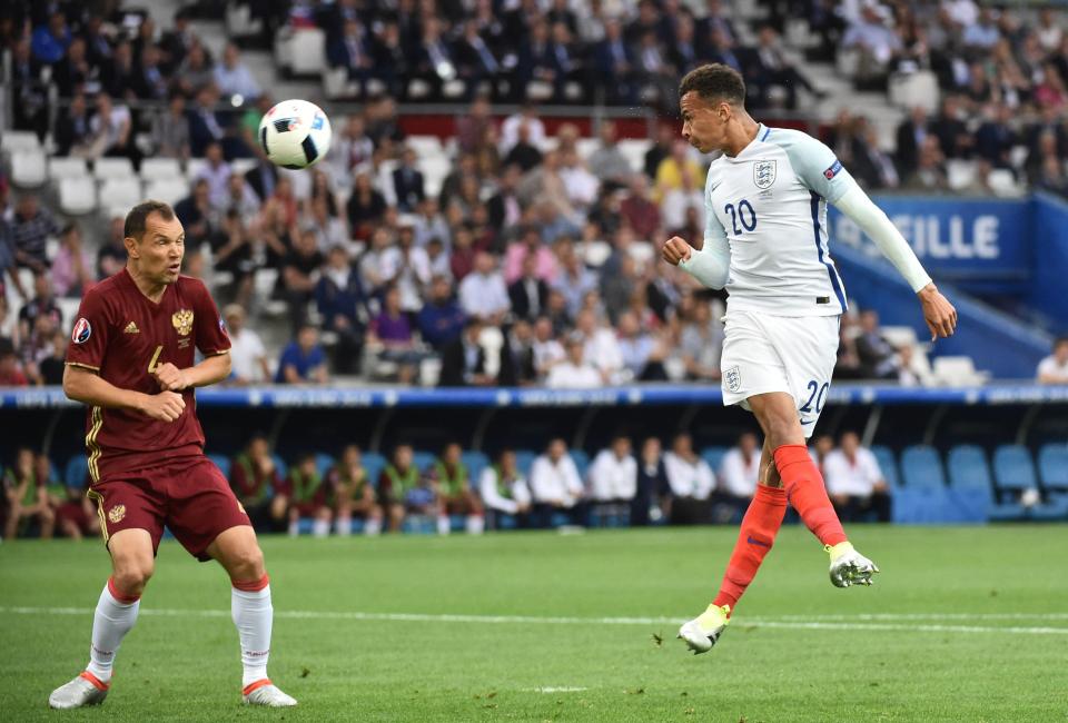  England midfielder Dele Alli heads the ball as Russia's defender Sergei Ignashevich grimaces at Euro 2016