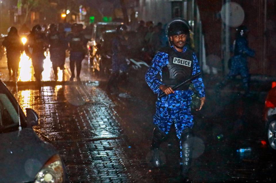  A riot policeman charges towards protesters after the government declared a state of emergency earlier this year