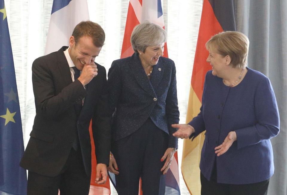 You're having a laugh... Theresa May, centre, enjoys a joke with French President Emmanuel Macron and German Chancellor Angela Merkel