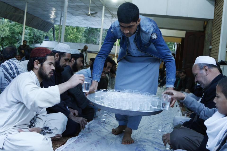  A man distributes water to people that attend a dinner in a mosque in Kabul, Afghanistan