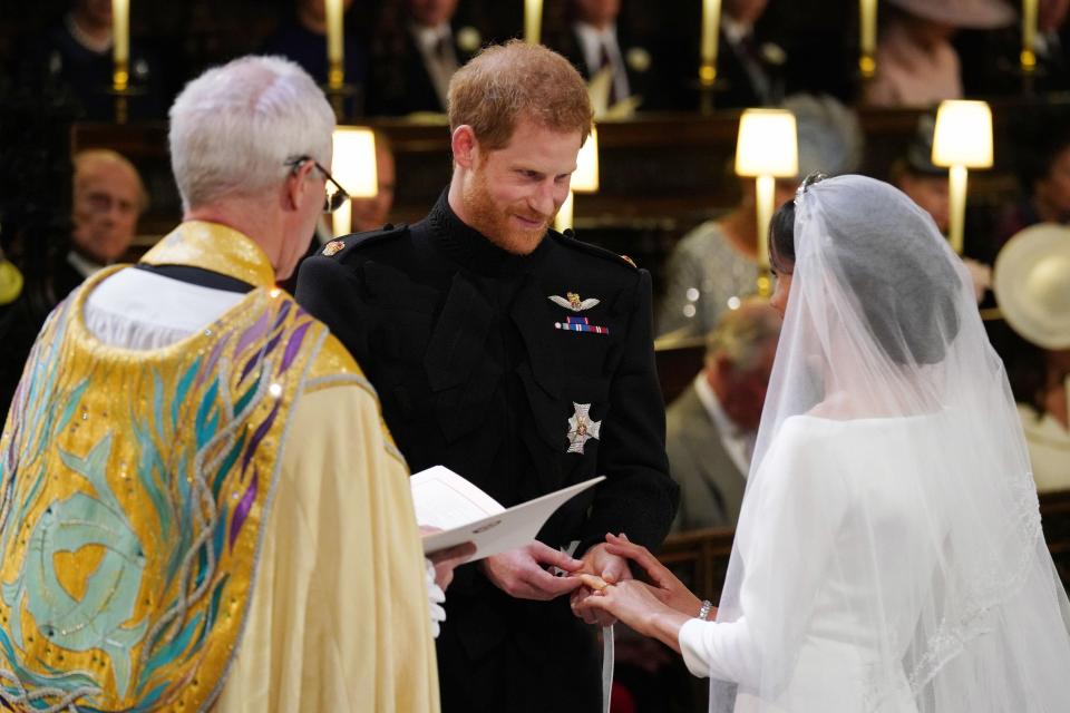  Prince Harry places the wedding ring on Meghan Markle's third finger