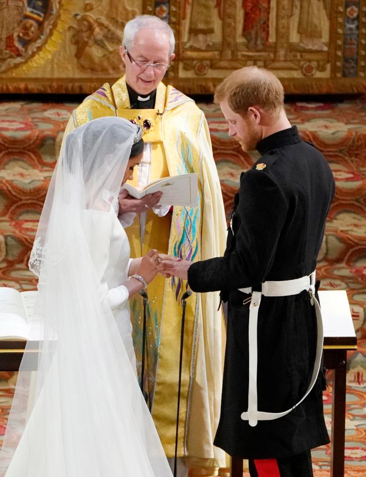  Meghan Markle places a wedding ring on Prince Harry's third finger at their wedding in St George's Chapel