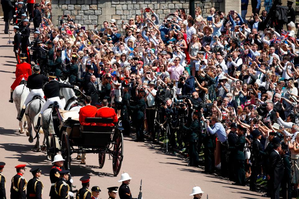  Cheering crowds wave banners as Meghan and Harry ride past