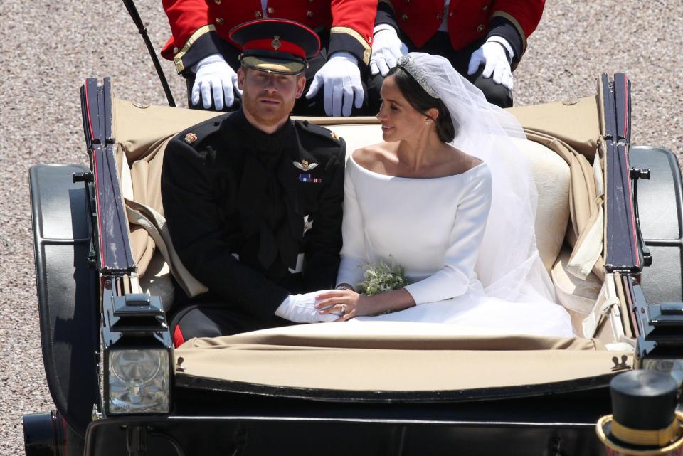  The married couple hold hands as they are led away by a horse drawn carriage