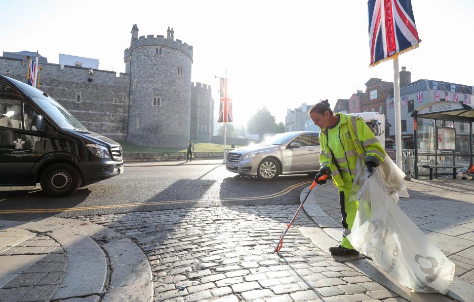  A street cleaner fills a bin bag with rubbish from the royal wedding celebrations outside Windsor castle