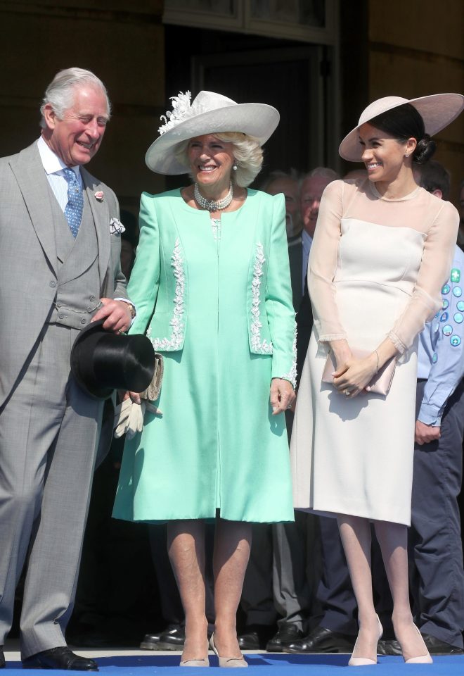 Meghan smiles next to the Prince of Wales and Camilla, having been walked down the aisle by her father-in-law