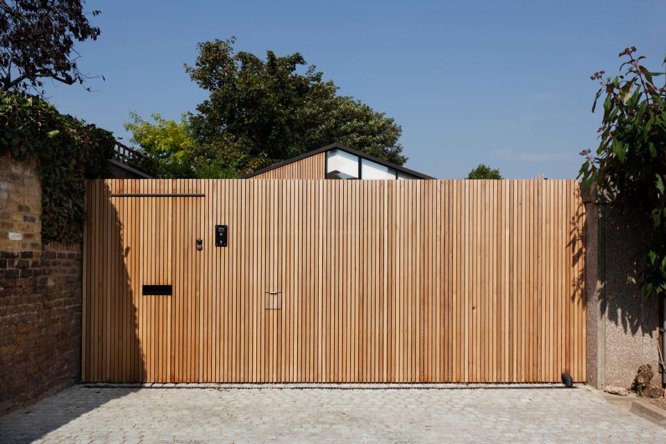  A tall wooden fence and gate provides privacy to the property that is located on a row of 16 garages