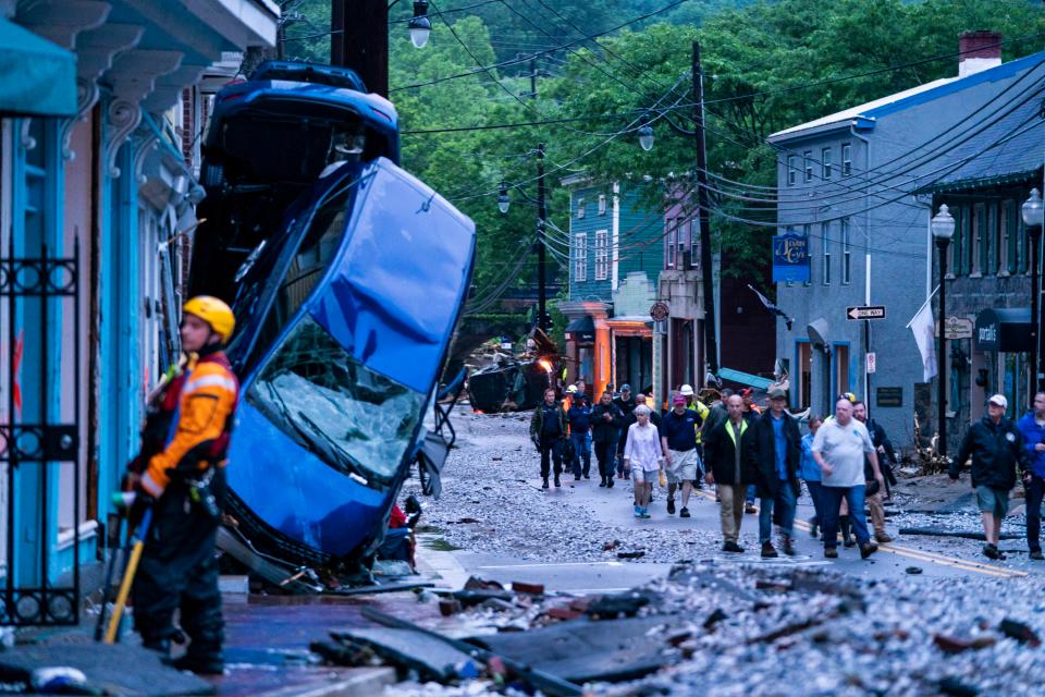  Residents walk through the debris after the flash floods