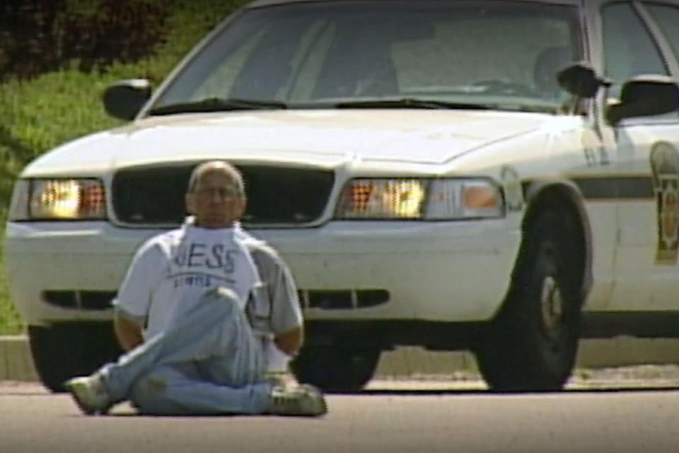  Brian Wells kneels down after being surrounded by police... seconds later he would blow up