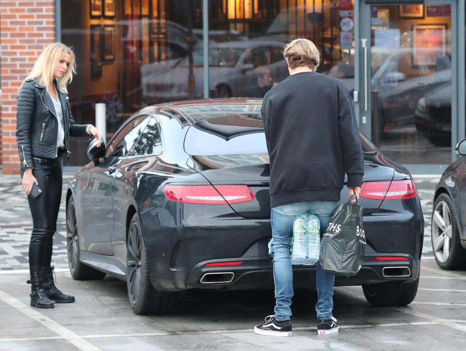 Karius puts some shopping into his sports car with girlfriend Daniella