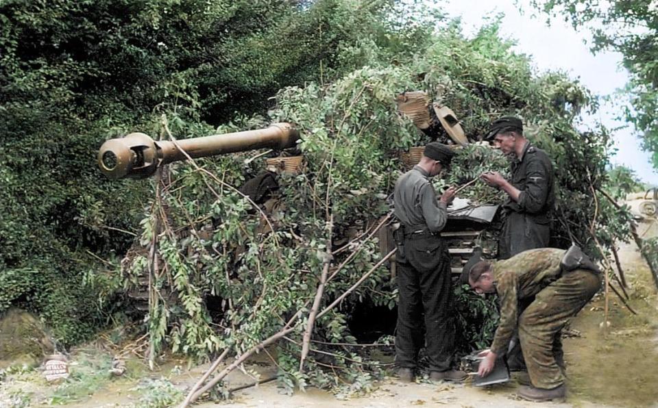  German troops camouflage a Panzer VI Tiger tank with undergrowth in the Normandy village of Villers-Bocage