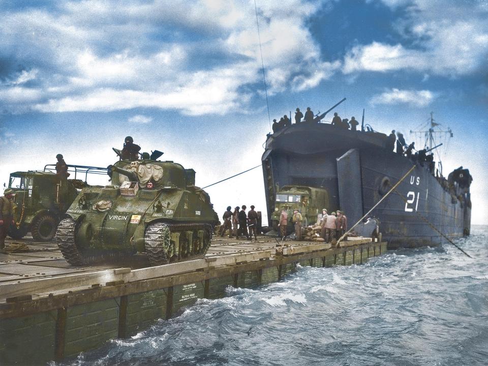  The USS LST-21, manned by the U.S. coastguard unloads British Army tanks and trucks onto a Rhino barge in the opening hours of their invasion of Gold Beach