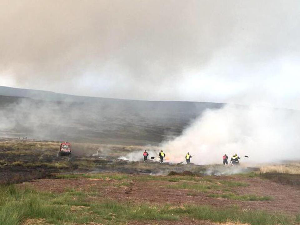 Firefighters are dwarfed by the huge plumes of smoke coming from the wildfire