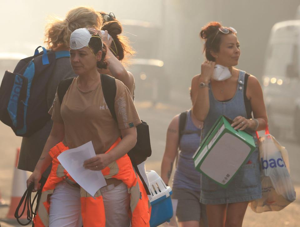  Residents from the village of Carrbrook wear face-masks to protect them from the smoke caused by the moor fire. More than 50 homes have been evacuated since the blaze started on Sunday