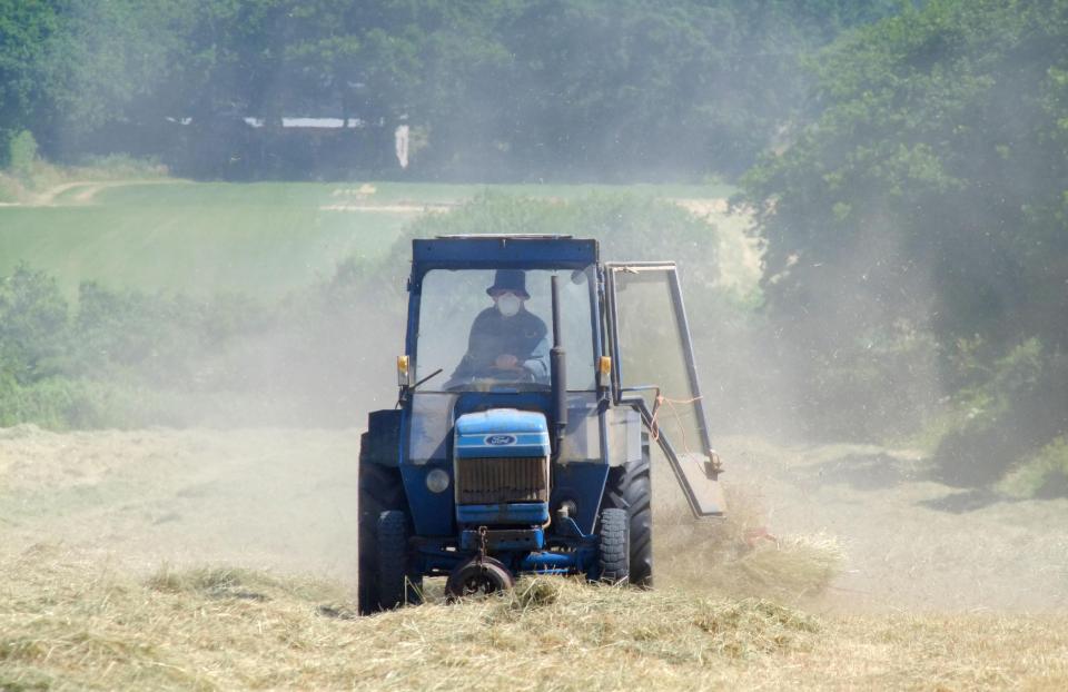 Dust rises from bone dry fields as a farmer makes hay whilst the sun shines in Ripe, East Sussex