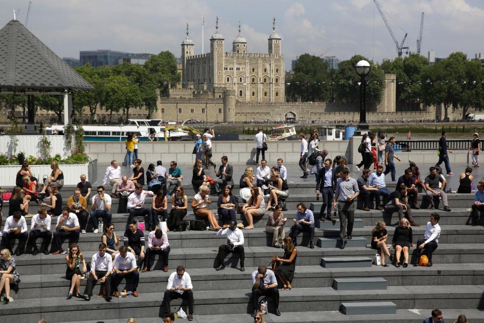 People relax in the sun during lunchtime as they sit on the steps of The Scoop, a riverside amphitheatre