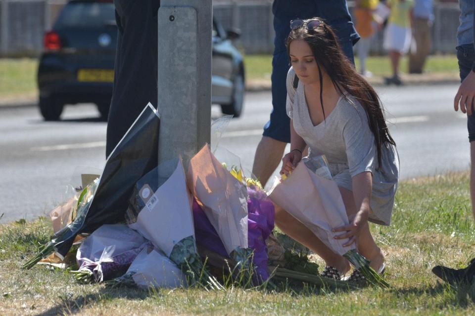  A woman leaves flowers alongside other tributes at the scene of the crash