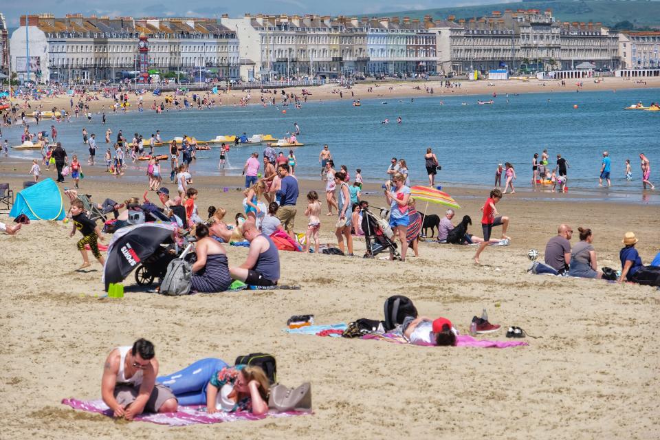  Crowds flock to Weymouth beach as the coastal fog clears and the temperature rises today in Dorset